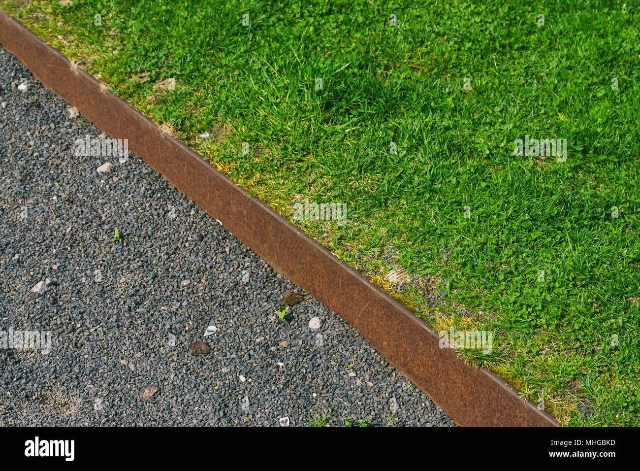 Rusty iron boundary between gravel path and lawn Stock Photo - Alamy