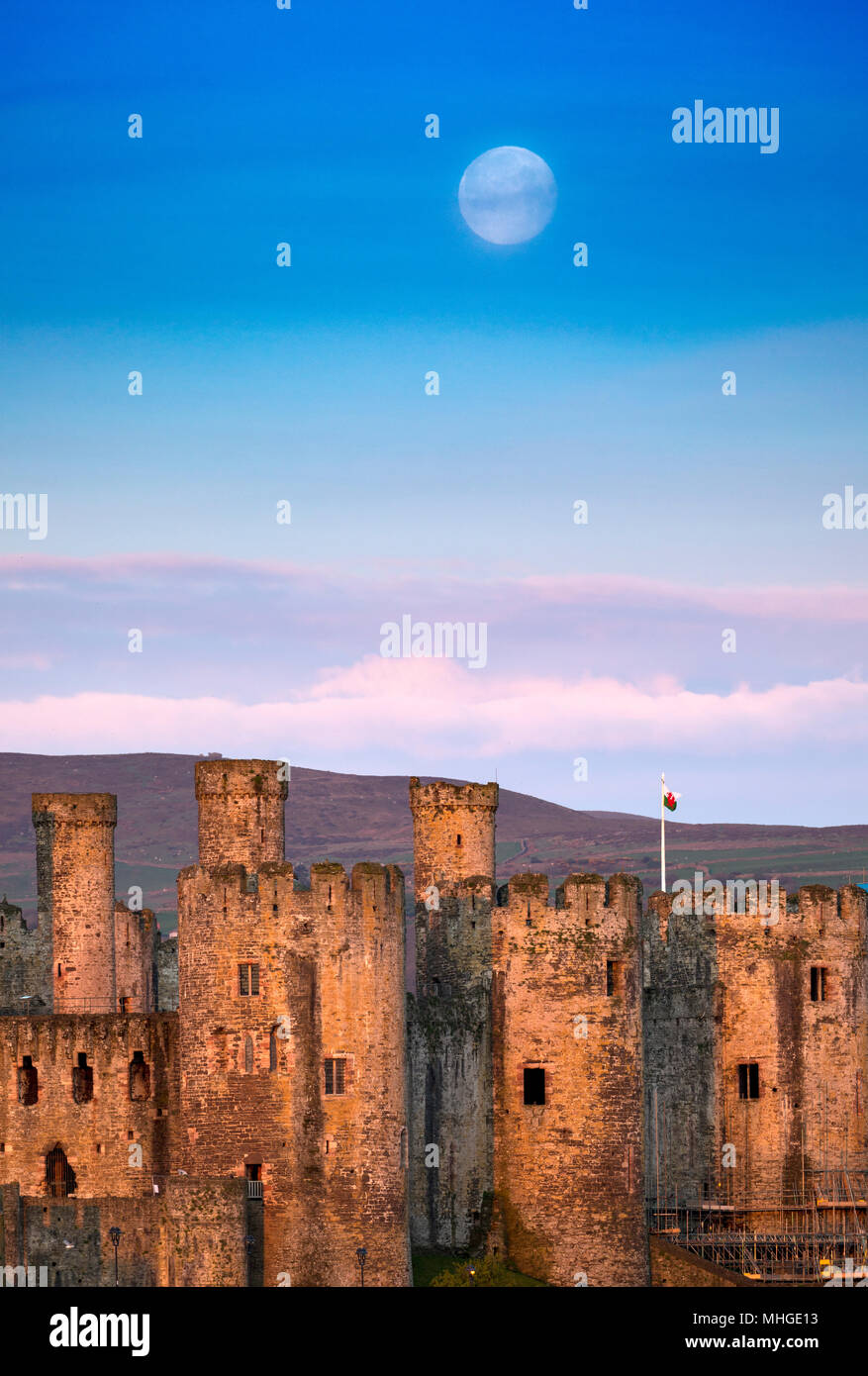 A beautiful sunrise dawn and setting moon over Conwy Castle and Carnedd Llewelyn and the start of Snowdonia National Park, Conwy, Wales, UK Stock Photo