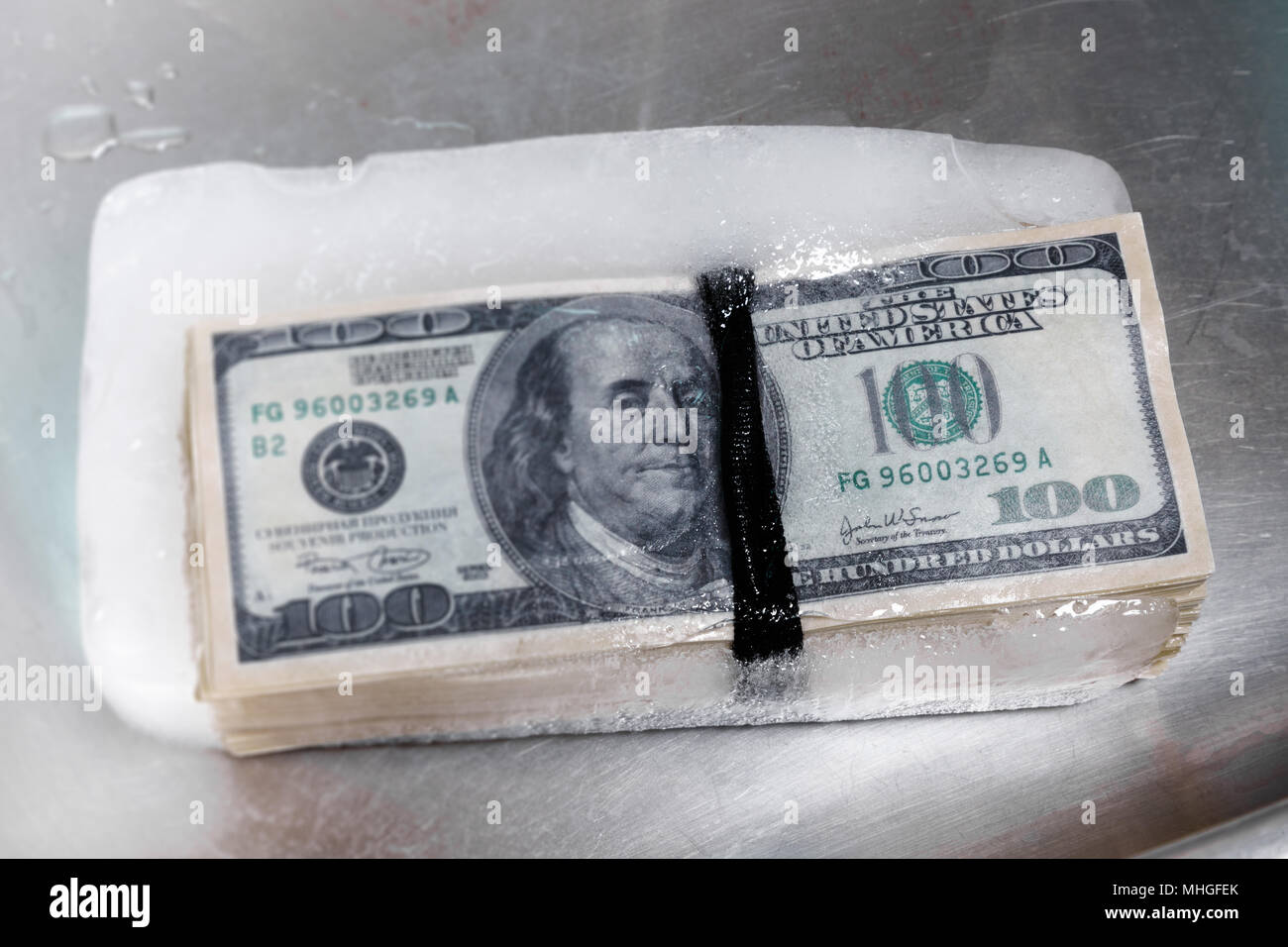 bundle of hundred-dollar bills frozen in ice Stock Photo