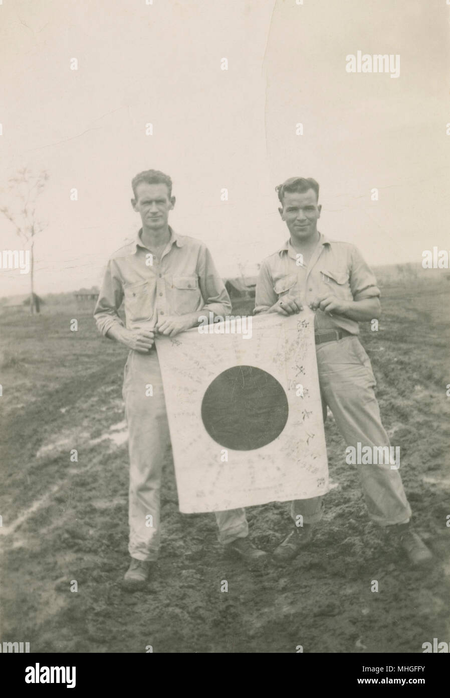 Antique 1944 photograph, two American soldiers hold a Japanese Good Luck Flag in New Guinea. SOURCE: ORIGINAL PHOTOGRAPHIC PRINT. Stock Photo