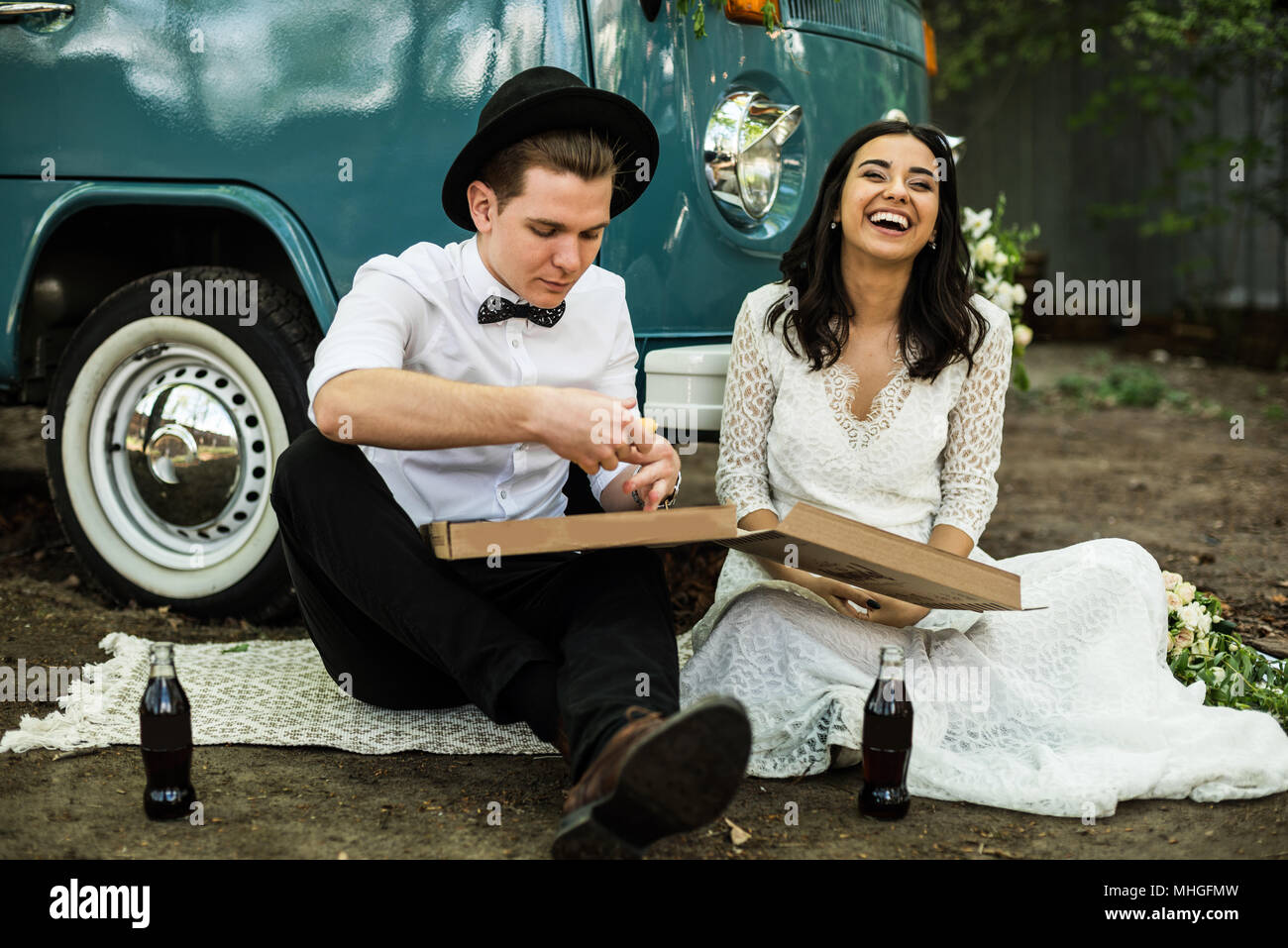 Cheerful happy young couple eat and drink near retro-minibus. Close-up. Stock Photo