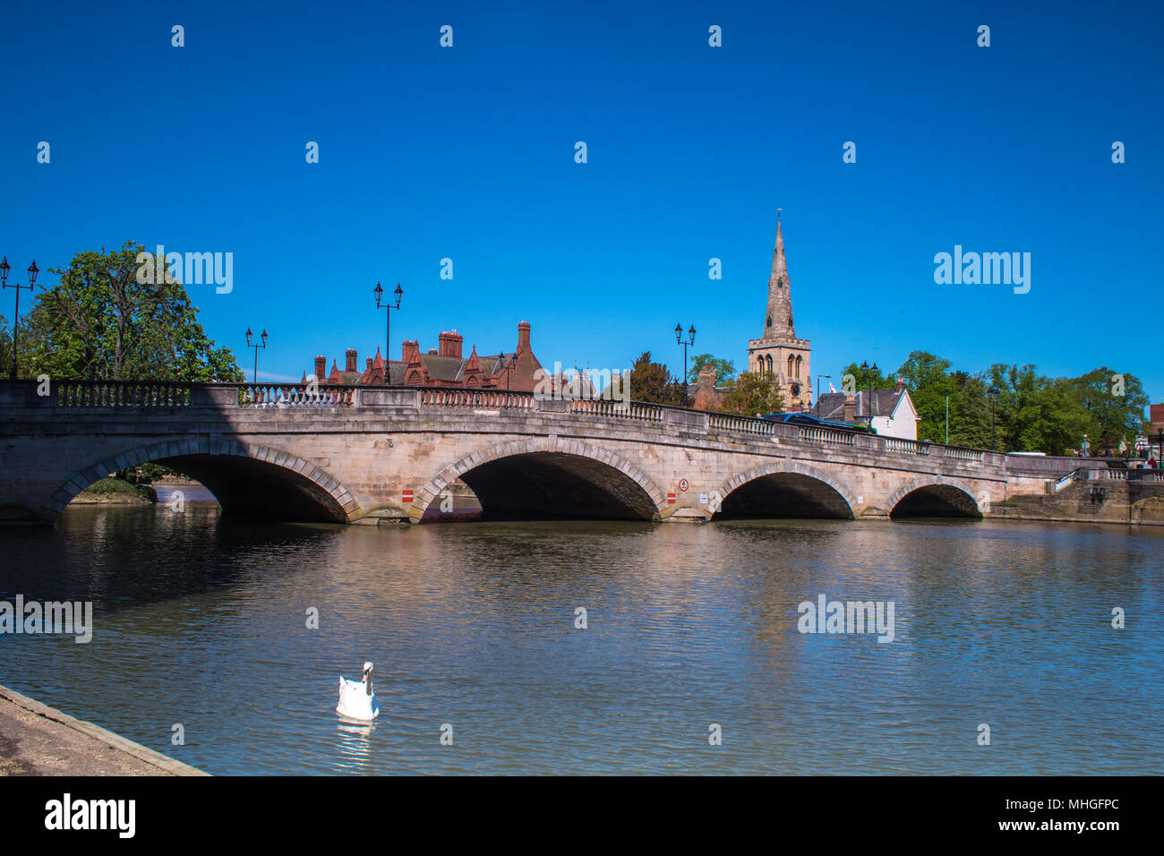 The River Great Ouse flows peacefully through Town Bridge in Bedford, UK, with the spire of St Paul's church in the background Stock Photo