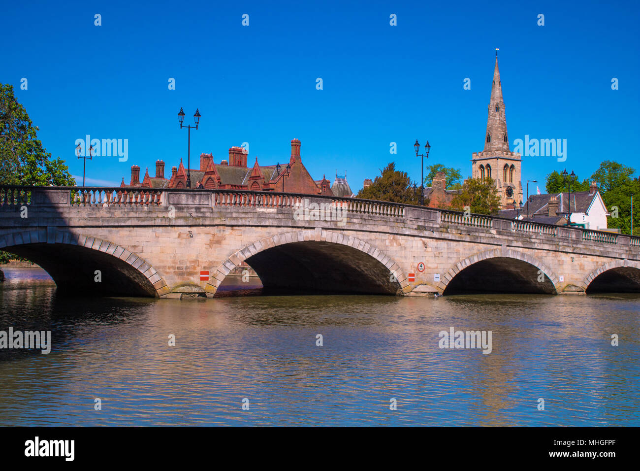 The River Great Ouse flows peacefully through Town Bridge in Bedford, UK, with the spire of St Paul's church in the background Stock Photo