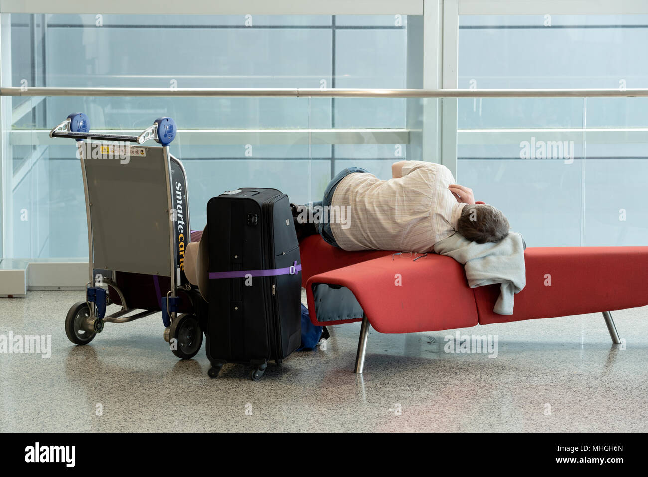 Passenger sleeping on bench in Miami International Airport, Miami