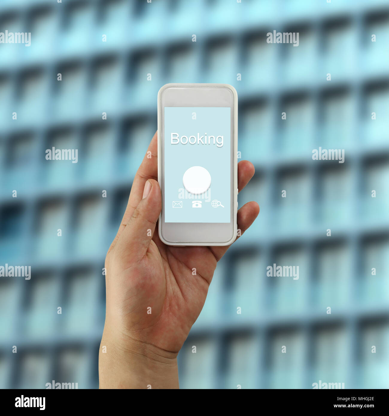 Hand of a businessman holding a smartphone and booking text concept in blur Skyscraper or high building background. Stock Photo