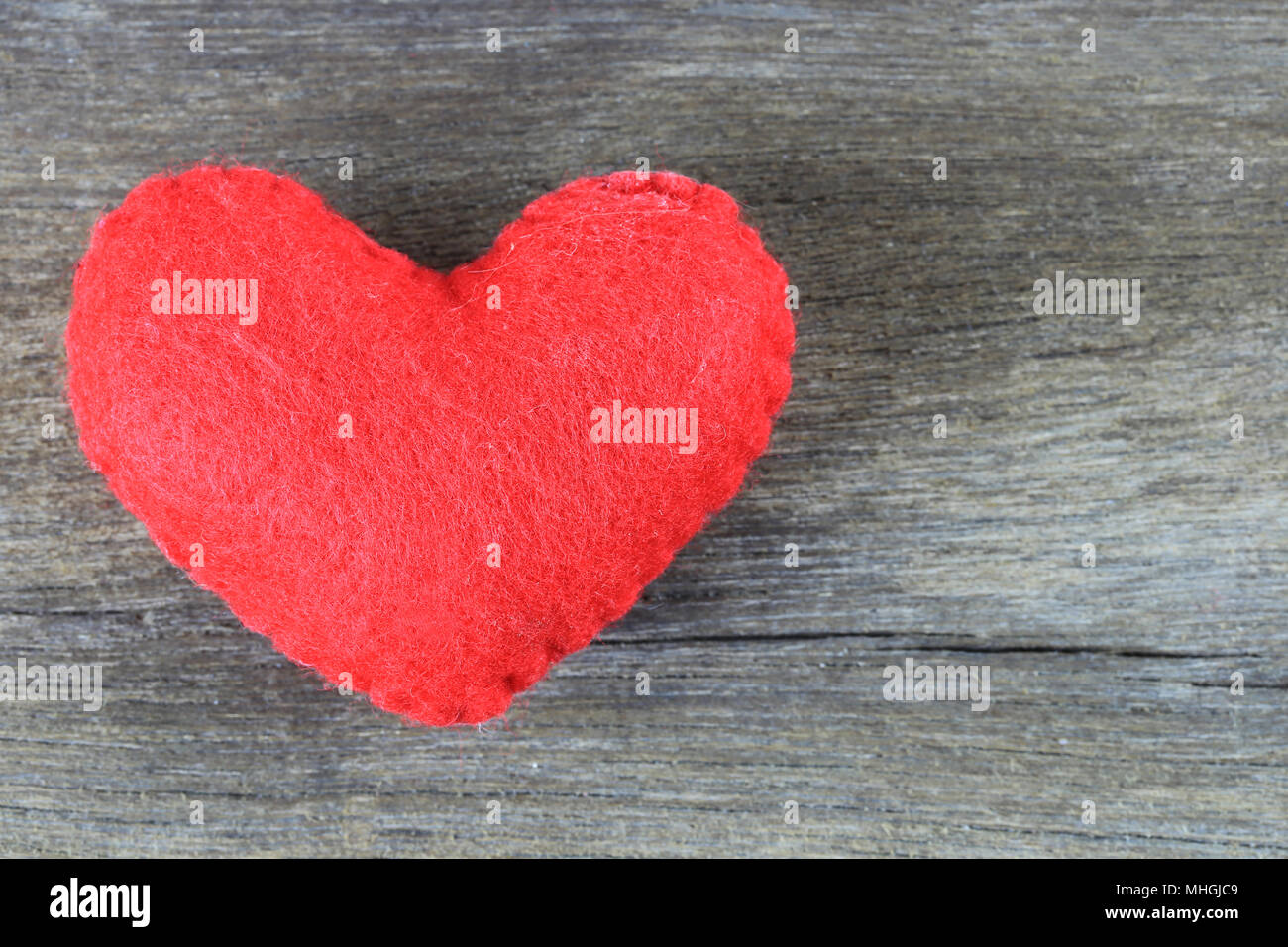 Red heart is placed on a brown wood floor and there is space available ...