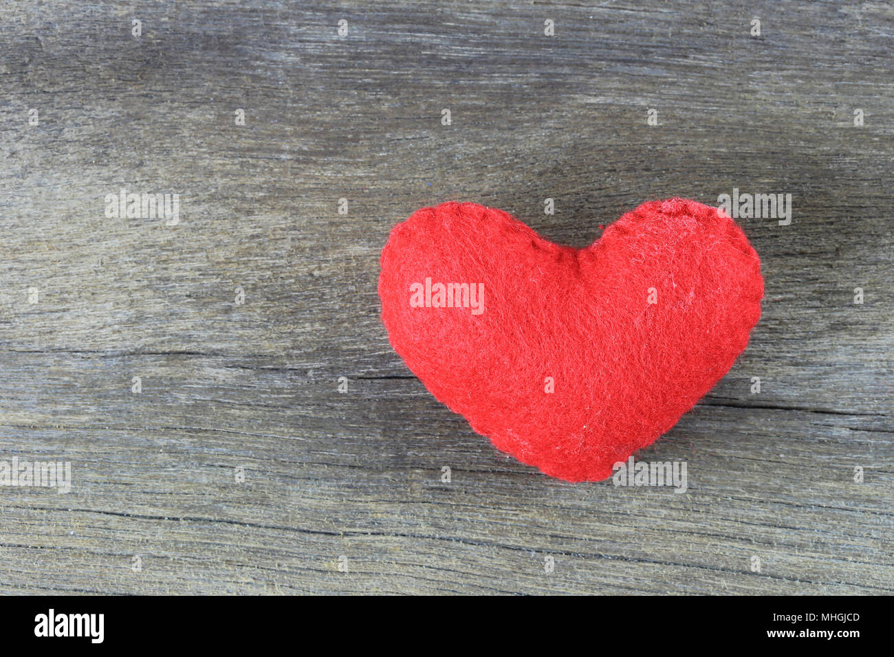 Red heart is placed on a brown wood floor and there is space available ...