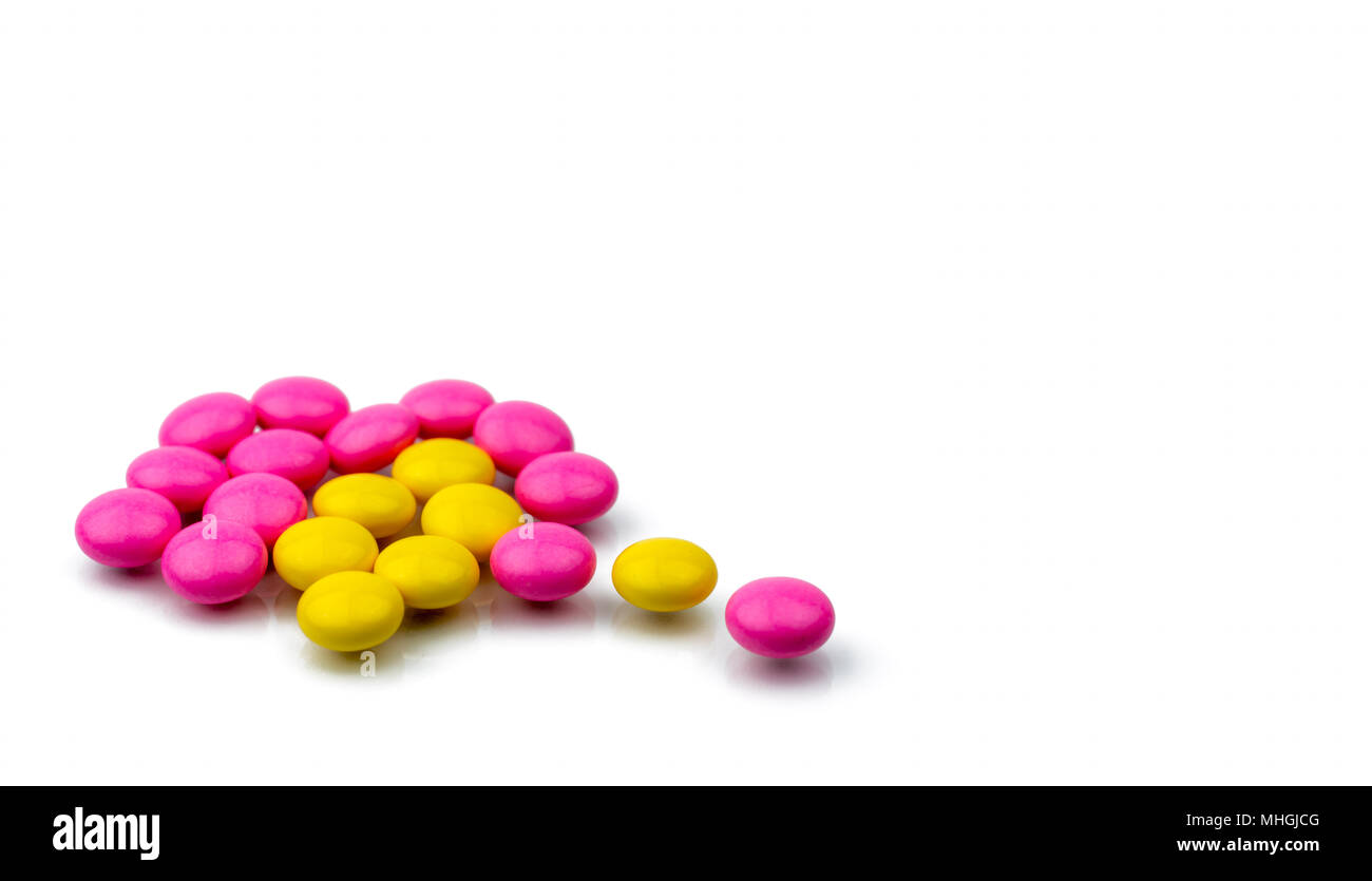 Pile of pink and yellow round sugar coated tablets pills isolated on white background with copy space. Colorful pills for treatment anti-anxiety, anti Stock Photo