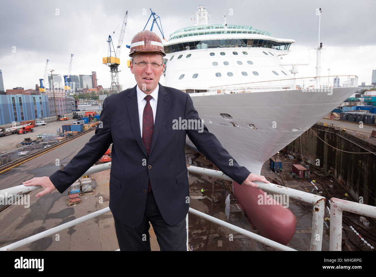 26 April 2018, Germany, Hamburg: Chairman of the Supervisory Board and director of technology at Luerssen, Klaus Borgschulte, standing on a podium in front of the cruise ship 'Brilliance of the Seas' by the shipping company Royal Caribbean International im Schwimmdock Elbe 17 on the grounds of the shipyard of Blohm Voss. The traditional shipyard is on a new course after having been taken over by the Luerssen-Gruppe of Bremen one and a half years ago. Photo: Christian Charisius/dpa Stock Photo