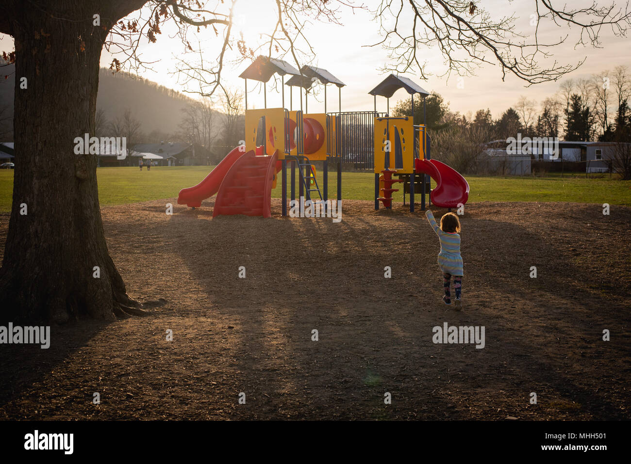A faceless young girl plays at a playground on a sunny afternoon. Stock Photo