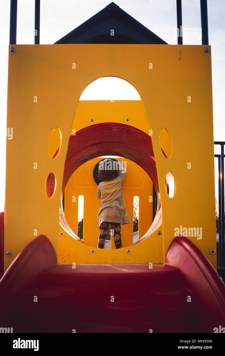 A faceless young girl plays at a playground on a sunny afternoon. Stock Photo