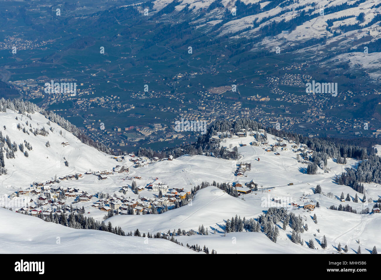 Top aerial view from Klingenstock peak on the whole Stoos village ski snowboard resort with new Stoosbahn railway and city of Schwyz in background Stock Photo