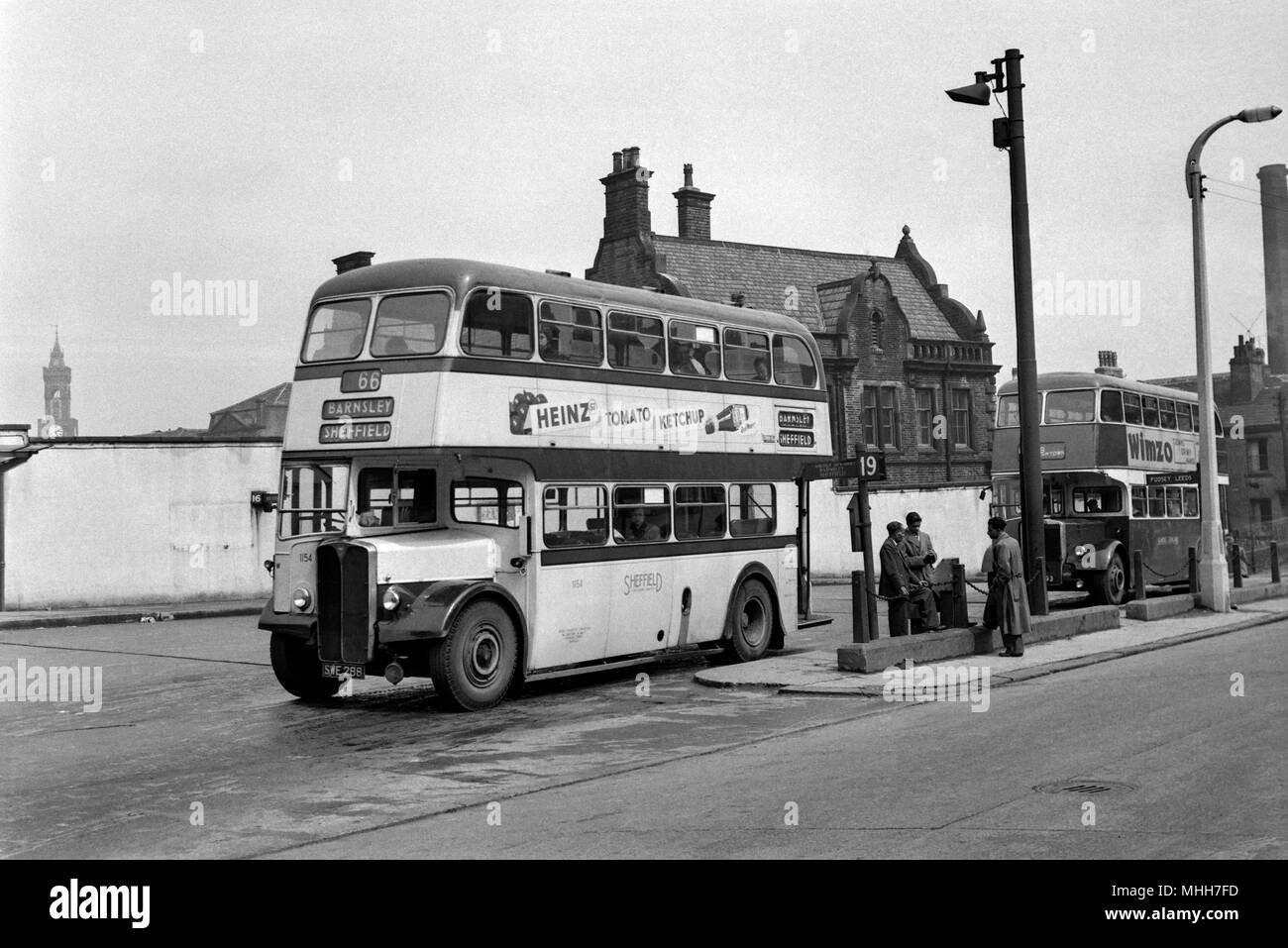 A small group of Asian men wait a bus in Sheffield, South Yorkshire. They could possibly be first generation immigrants seeking a better life 1960 Stock Photo