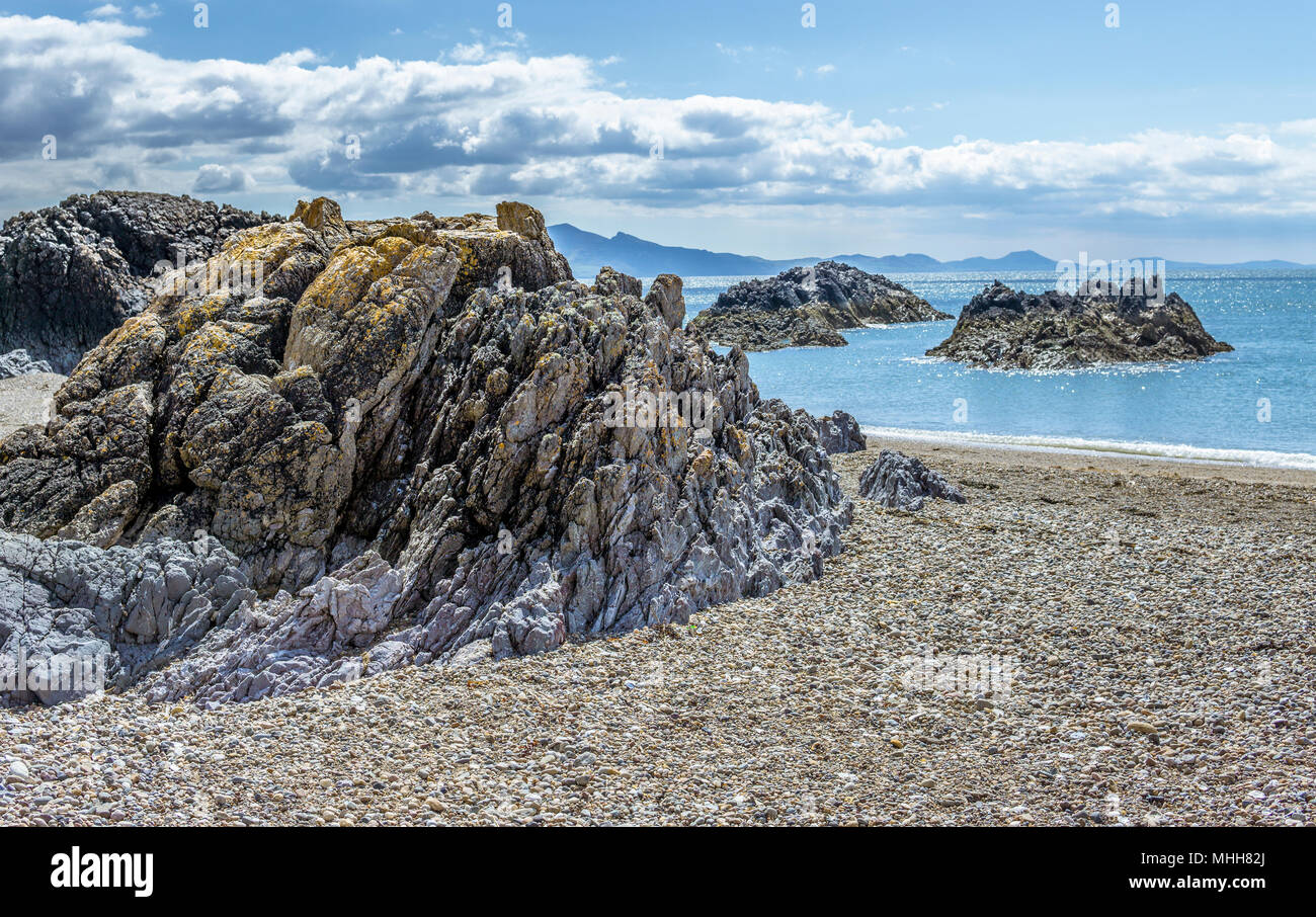 A view out in to the Irish sea at the tip of Llanddwyn Island on Anglesey. North Wales. The mountains of the Llyn peninsula in the background.. Stock Photo