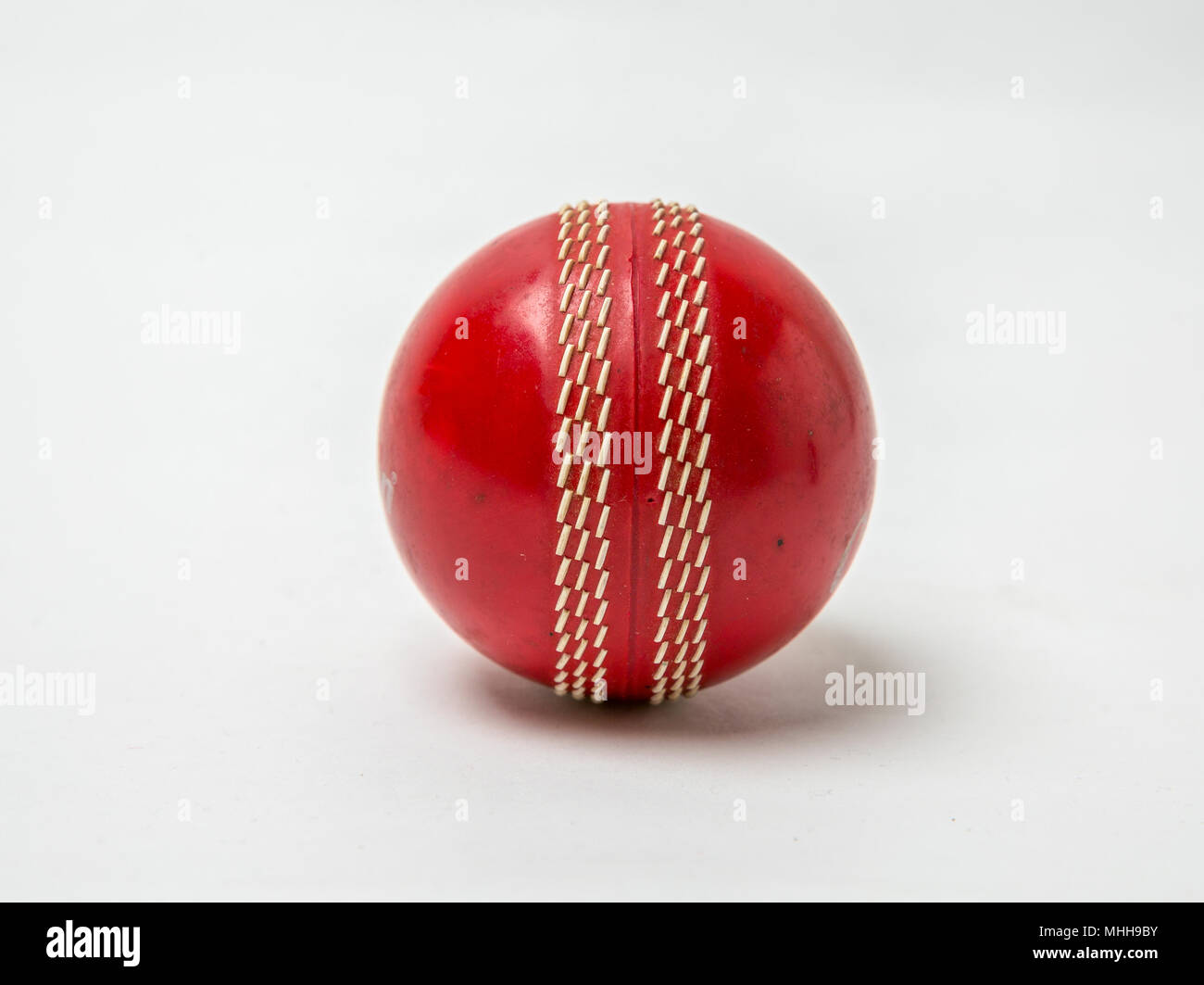 Close-up shot of a red Cricket ball on white background. Stock Photo