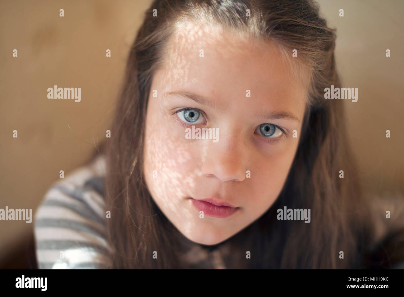 straight looking girl portrait with window curtain shadow on face Stock Photo