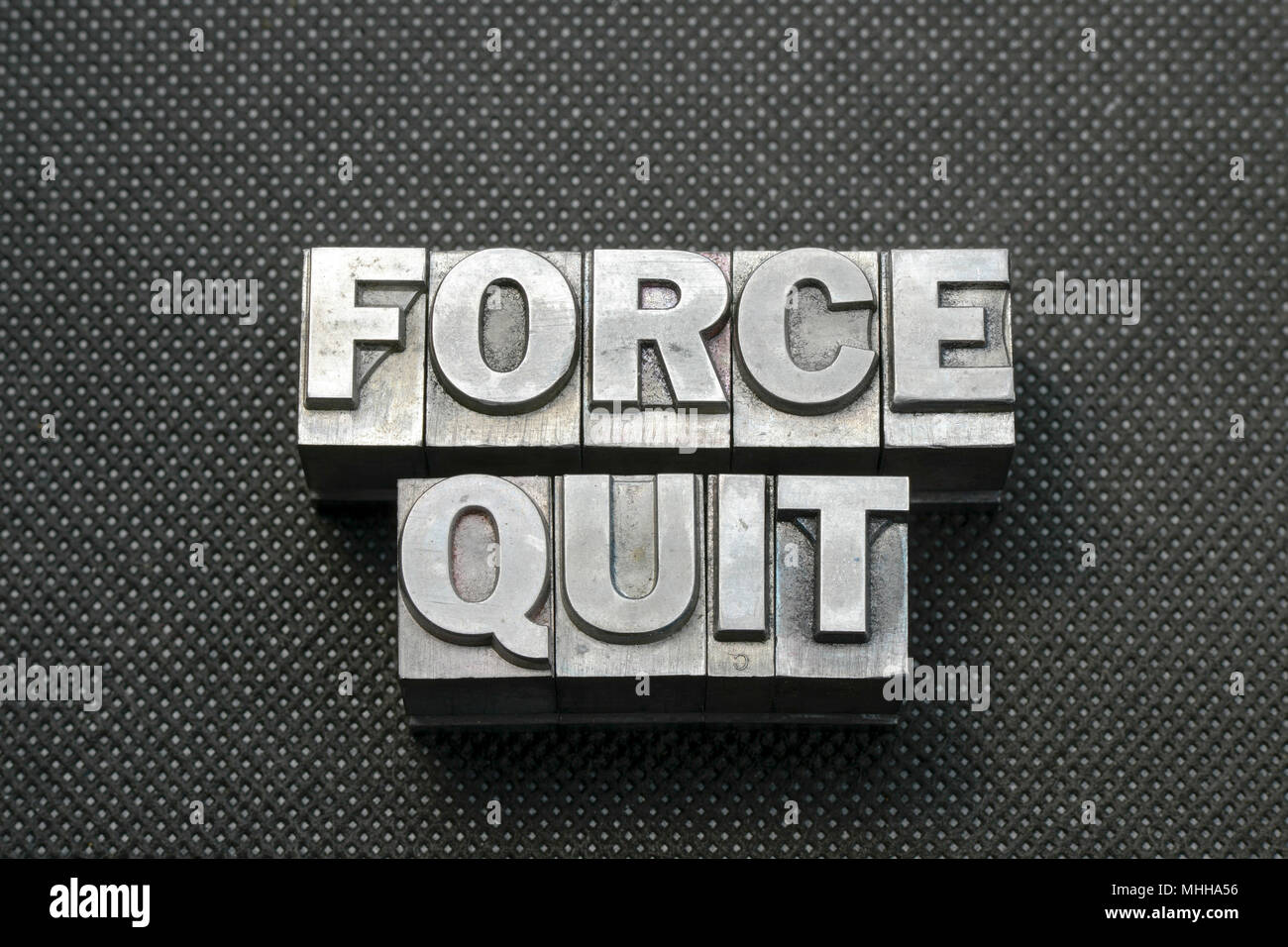 force quit question made from metallic letterpress blocks on black perforated surface Stock Photo