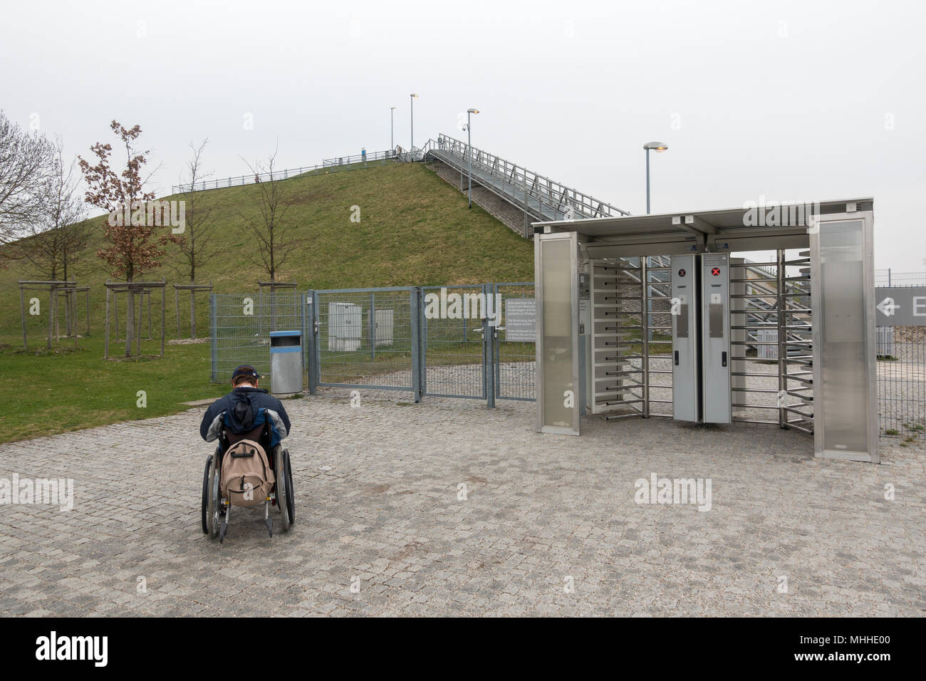 A man in a wheelchair looking up at visitor hill he cannot access in the Visitors Park at Munich Airport, Munich, Germany. Stock Photo
