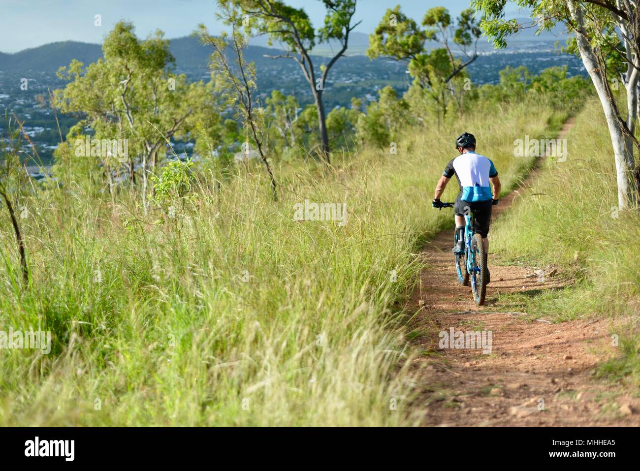 Male bicycle rider on a mountain bike going down a hill on a gravel track,  Mount Stuart hiking trails, Townsville, Queensland, Australia Stock Photo
