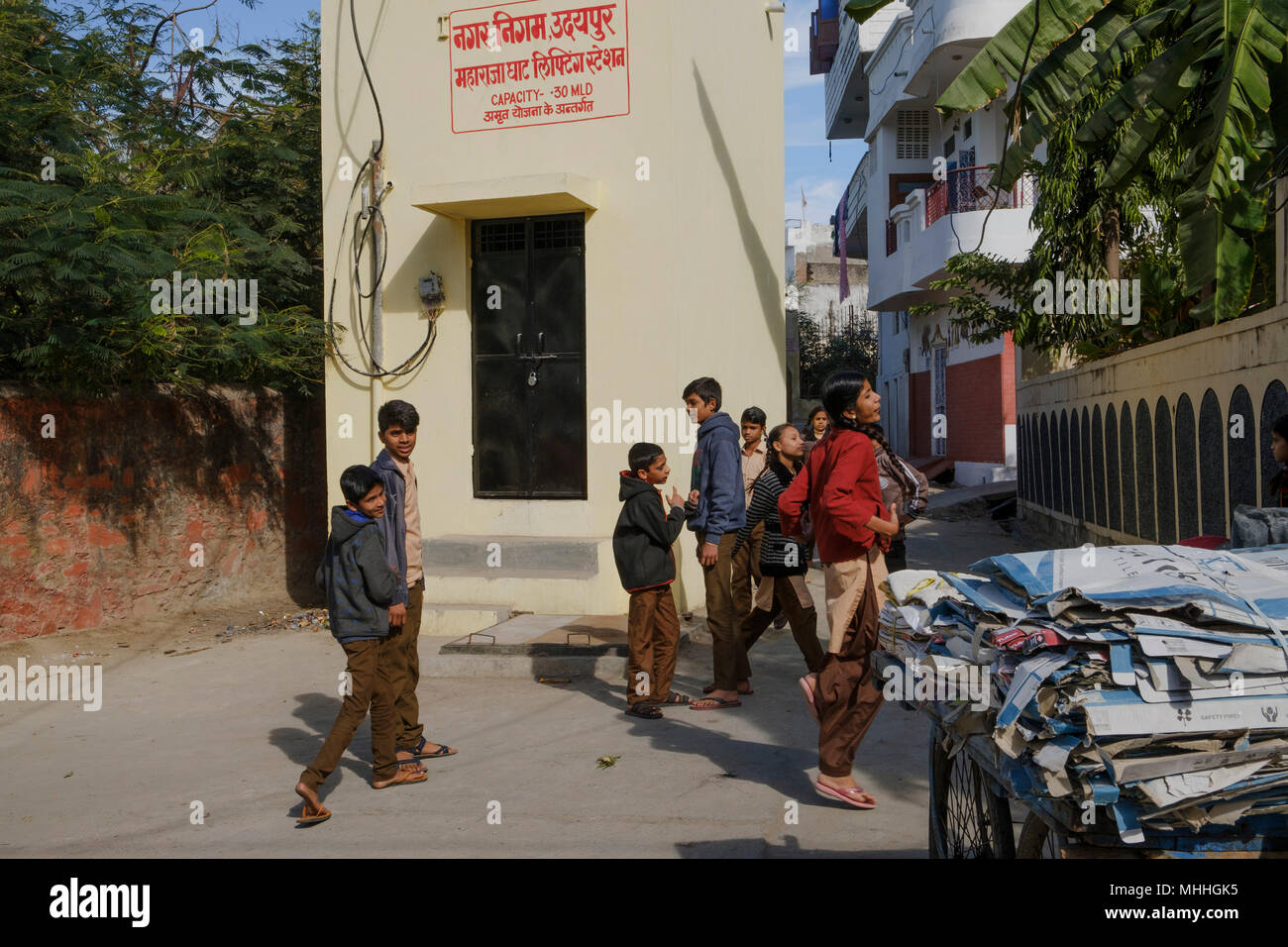 School children on a street corner by a cart with cardboard for recycling. Udaipur, also known as the City of Lakes, The Venice of the East, is the historic capital of the kingdom of Mewar, Rajasthan. Stock Photo
