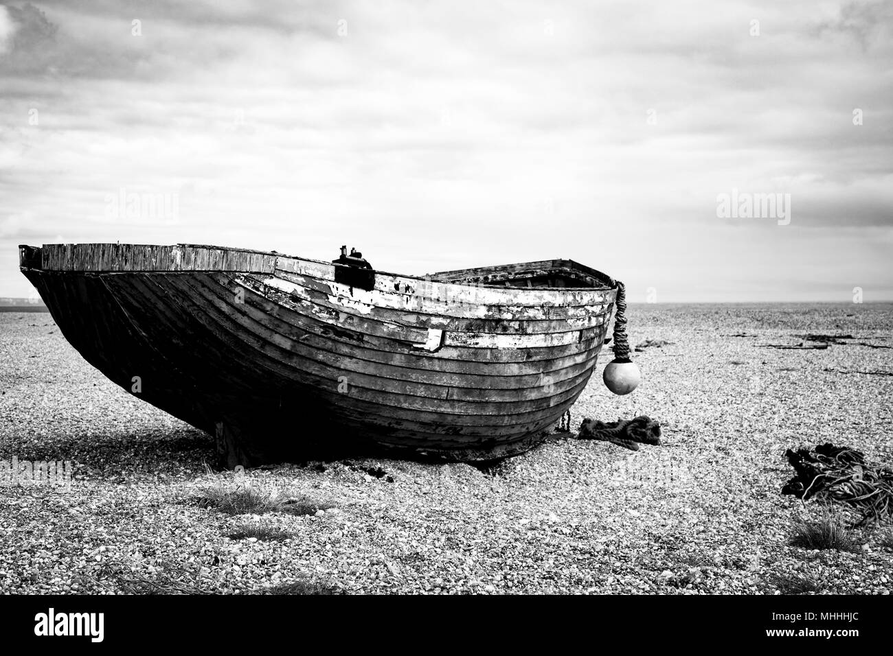 Old wooden fishing boat on shingle by the shore, English Channel Stock Photo