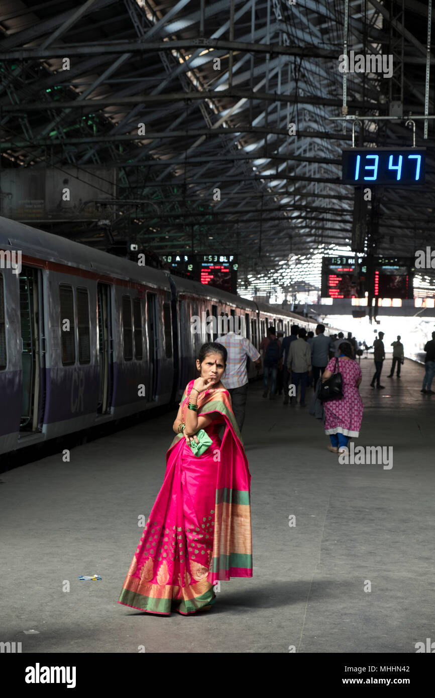 India - Mumbai - Woman in a spree waiting on the platform at The Chhatrapati Shivaji Terminus, formerly known as Victoria Terminus. The railways station, is a Unesco World Heritage Site. The station was designed by Frederick William Stevens according to the concept of Victorian Italianate Gothic Revival architecture and meant to be a similar revival of Indian Goth (classical era) architecture. The station was built in 1887 in the Bori Bunder area of Mumbai to commemorate the Golden Jubilee of Queen Victoria Stock Photo