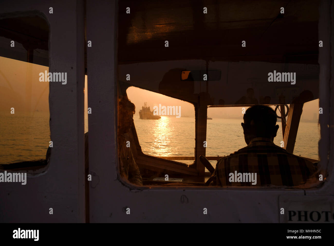 India - Mumbai. Captain on the bridge. Ships in Mumbai harbour at sunset. Stock Photo