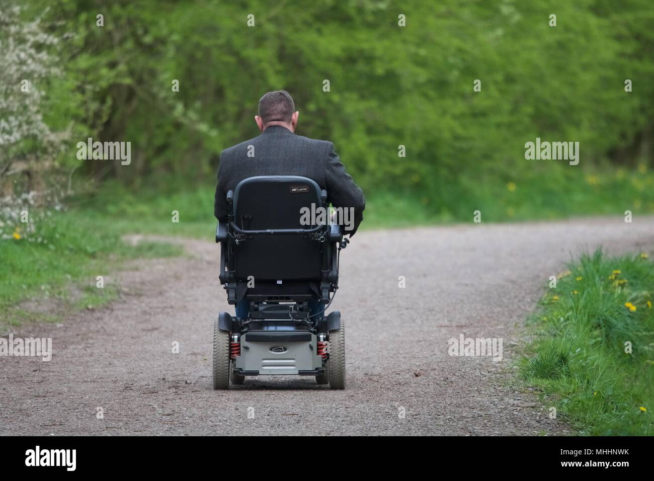 A man in an electric wheelchair drives along the Sett Valley Trail in New Mills, Derbyshire. Stock Photo