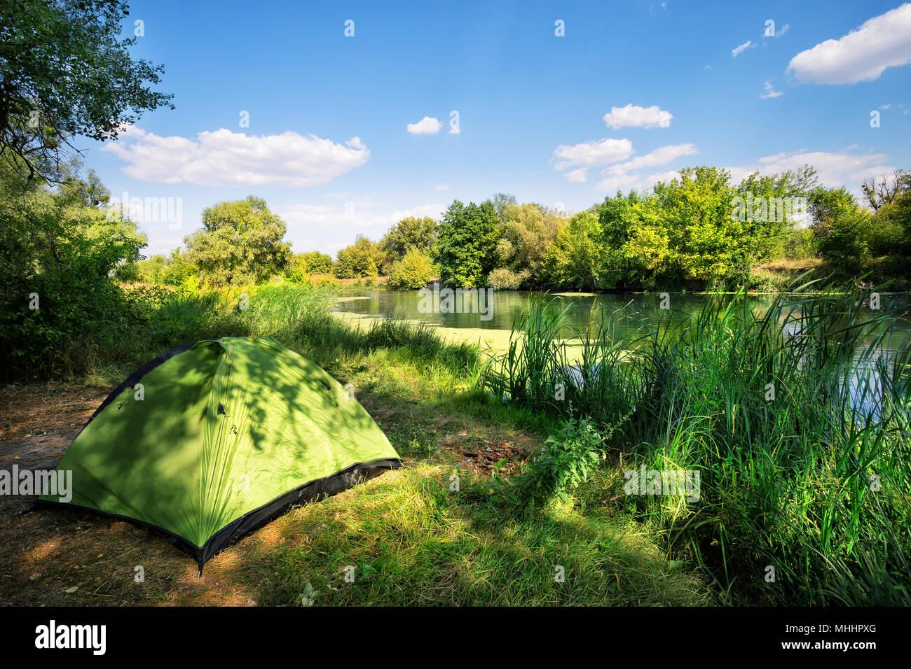 Green tent on the river bank Stock Photo