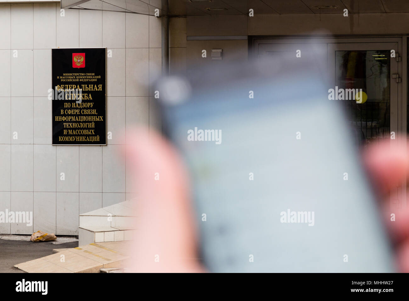 MOSCOW, RUSSIA - APRIL 30, 2018: Smartphone with Telegram app in hand on the background of a sign at the entrance to the Roskomnadzor building. After  Stock Photo