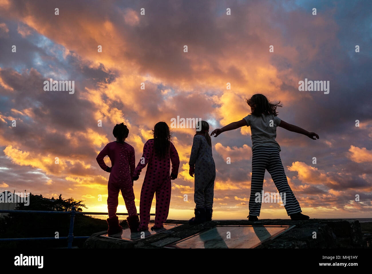 4 children watch the sunset on summer holidays in Devon, UK Stock Photo