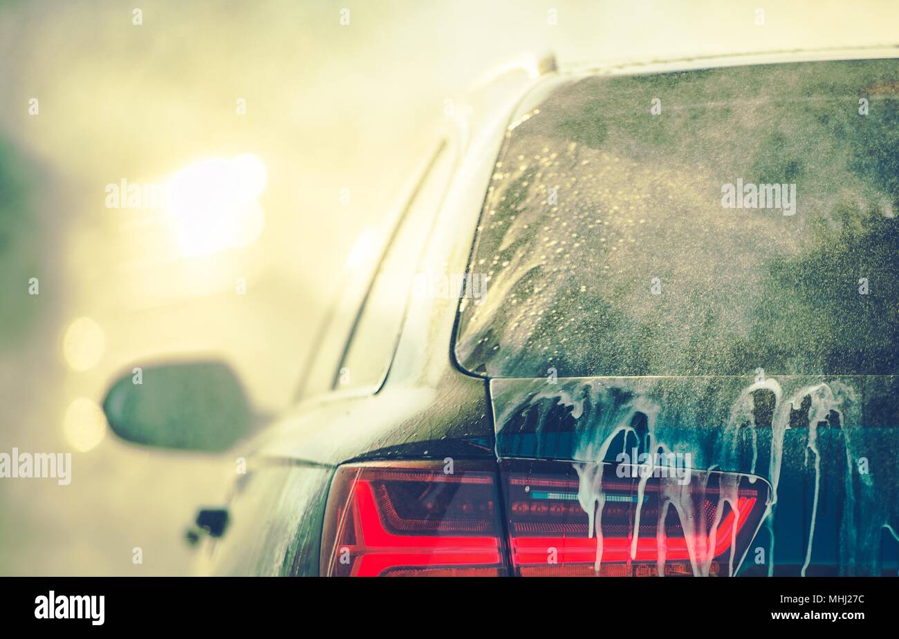 Cleaning Vehicle in the Car Wash. Closeup Photo. Auto Body Covered by