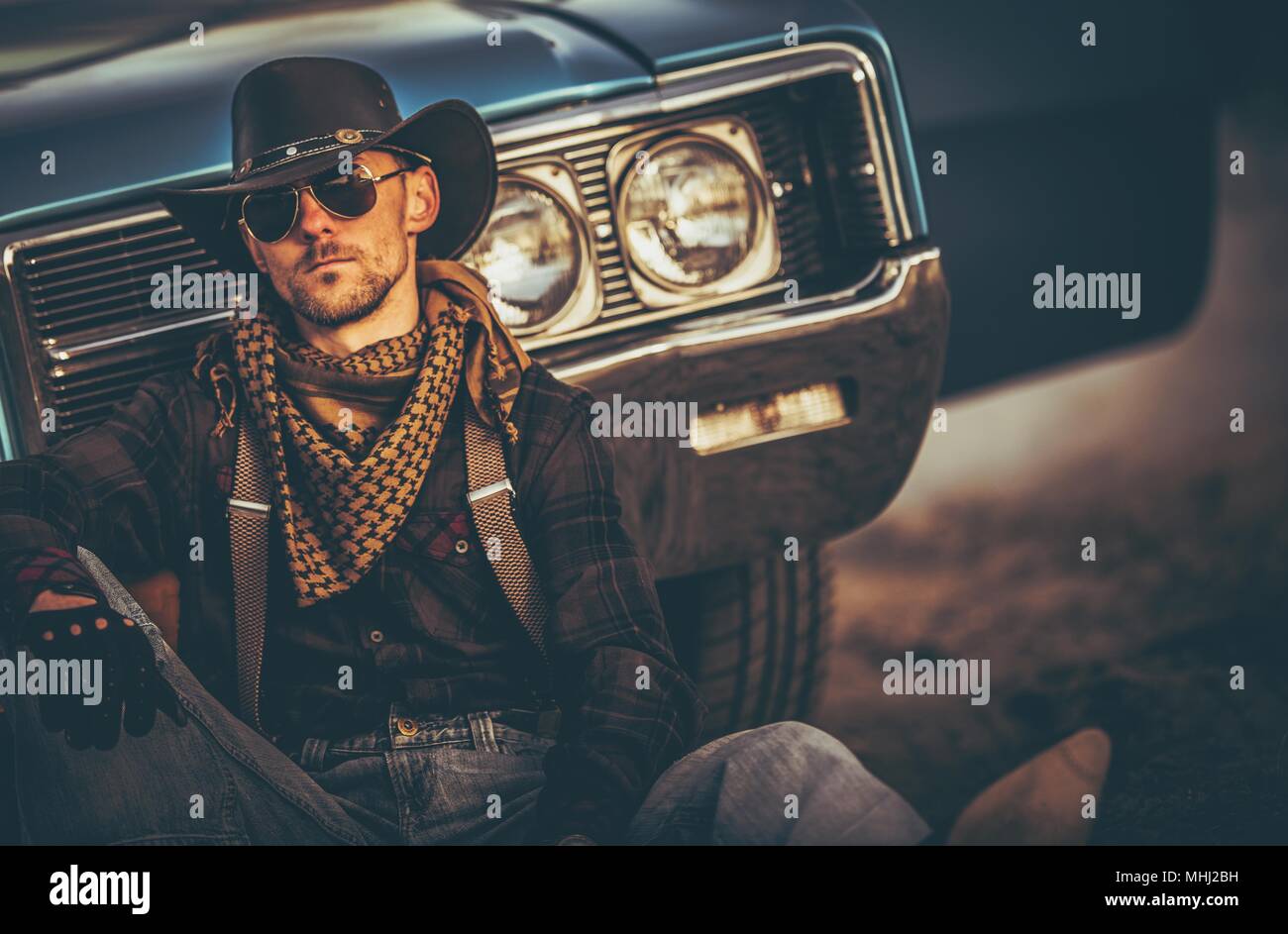 The Men of the Far West. Caucasian Western Wear Men in His 30s Relaxing in Front of His Classic Muscle Car. American West. Stock Photo