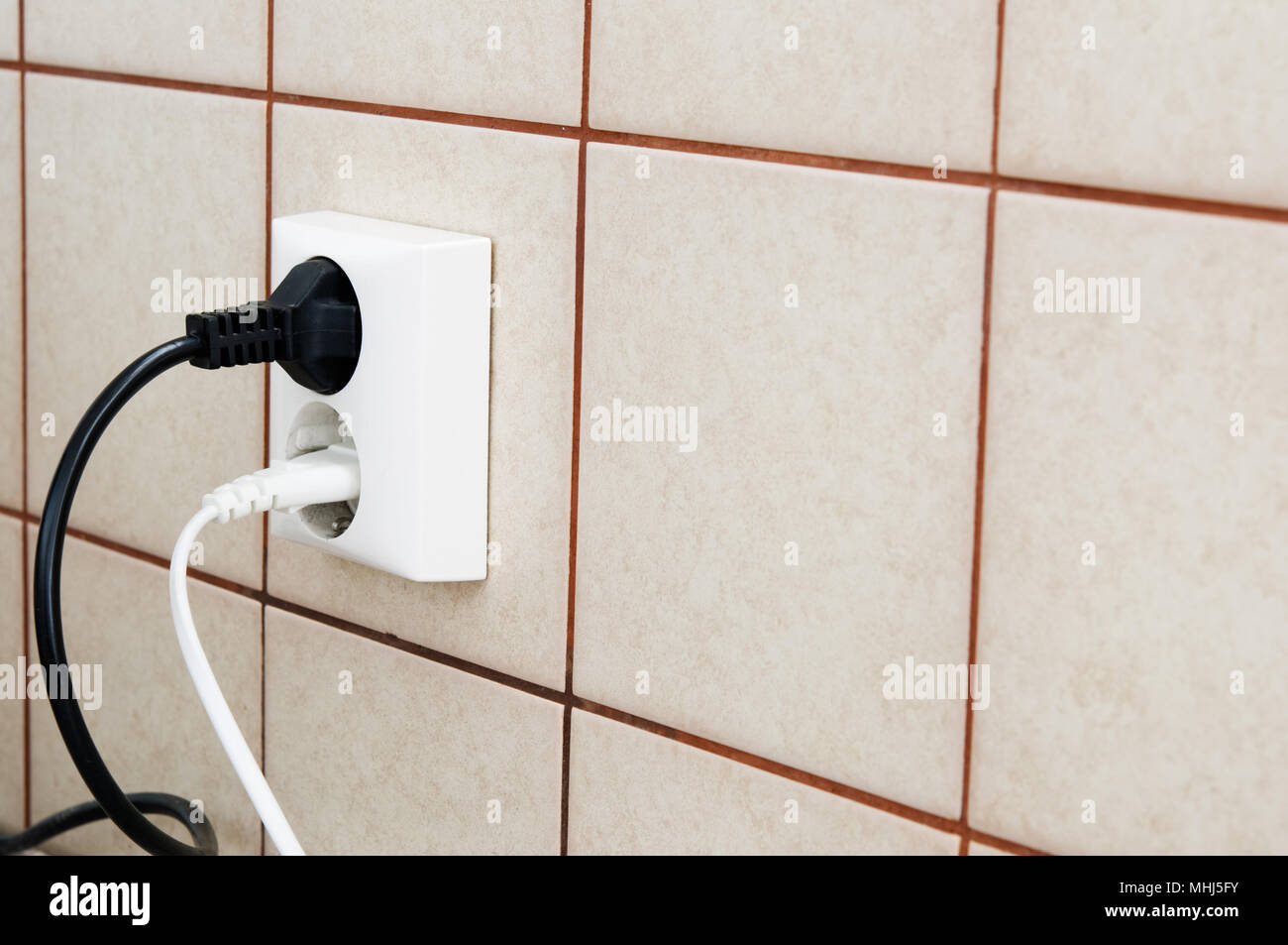 Plugs connected to the outlet in a wall. Stock Photo