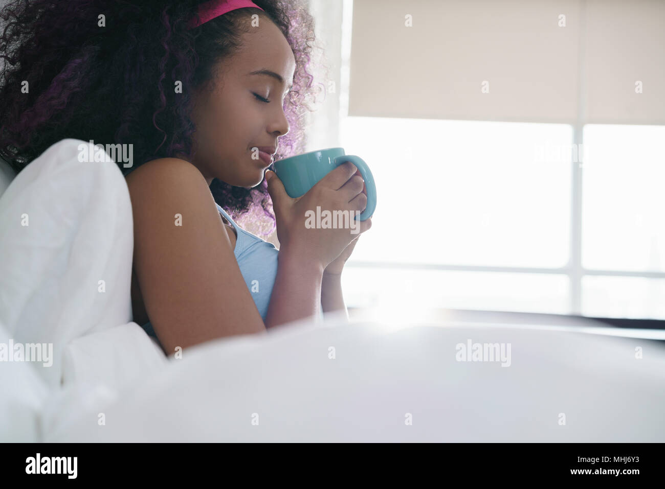 Black Woman Drinking Coffee In Bed Smiling Stock Photo