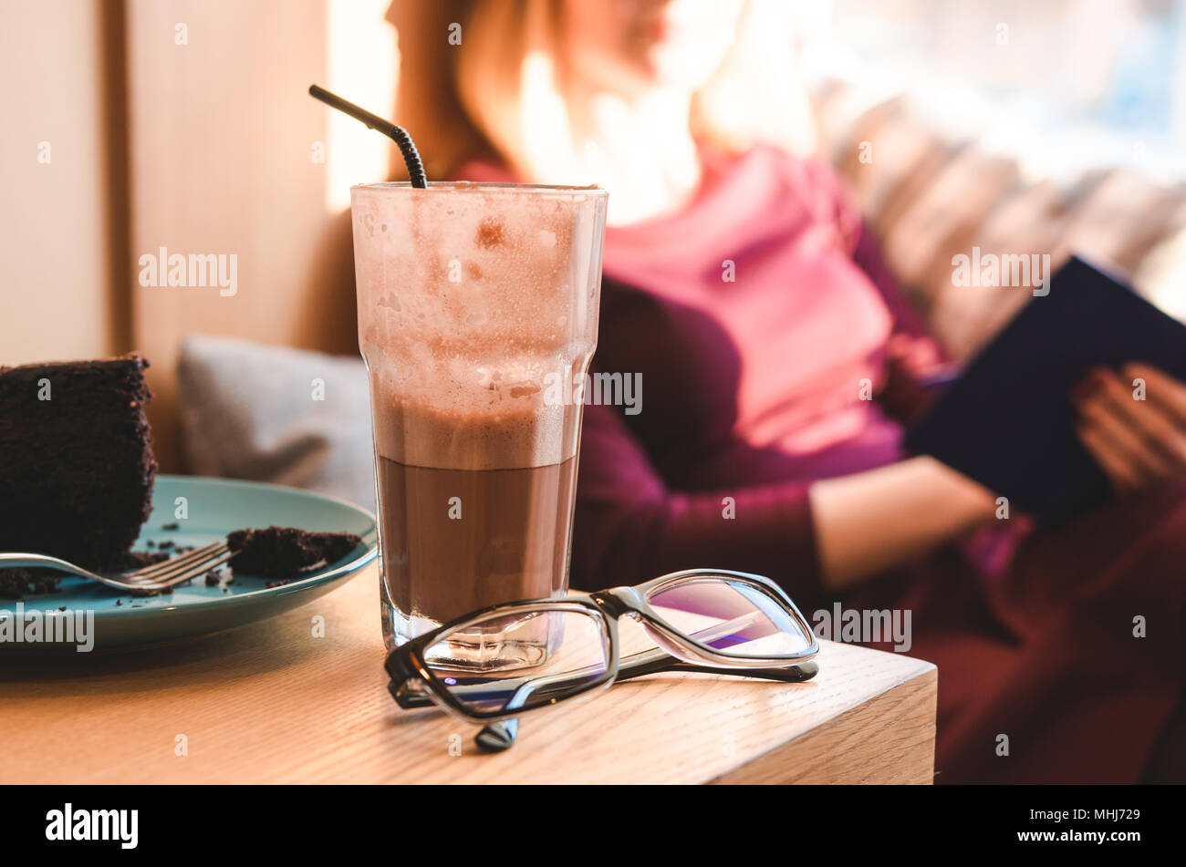 Still life: glasses, cake and coffee. Beautiful girl reading book. Cozy and warm Stock Photo
