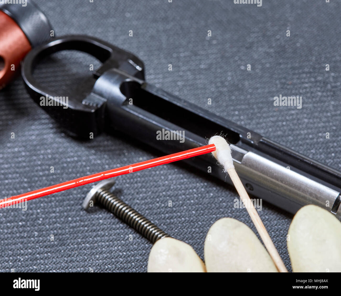 Applying lubricating gun oil to a cotton swab in preparation to