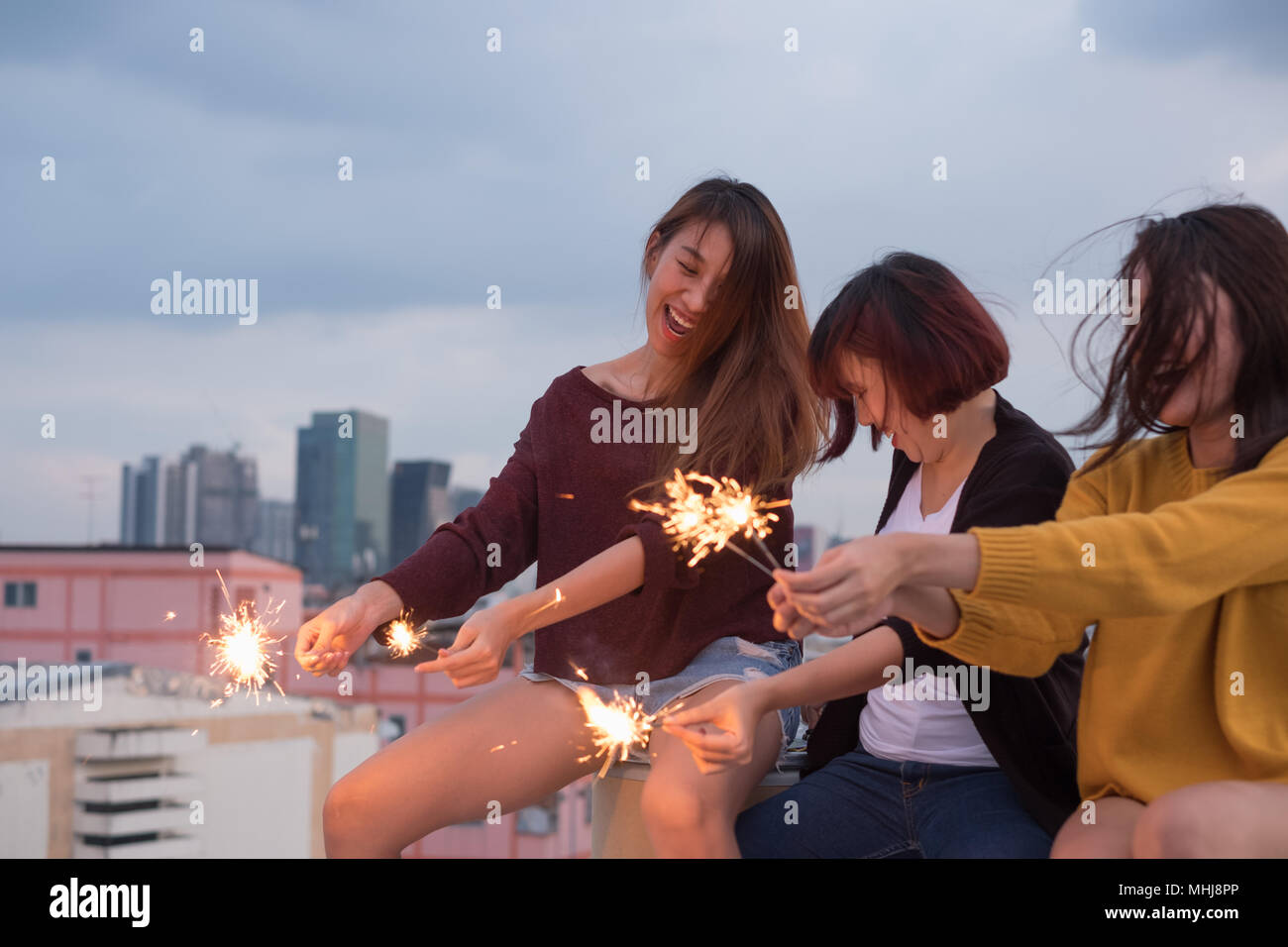 Happy group of asia girl friends enjoy and play sparkler at roof top party at evening sunset,Holiday celebration festive,teenage lifestyle,freedom and Stock Photo