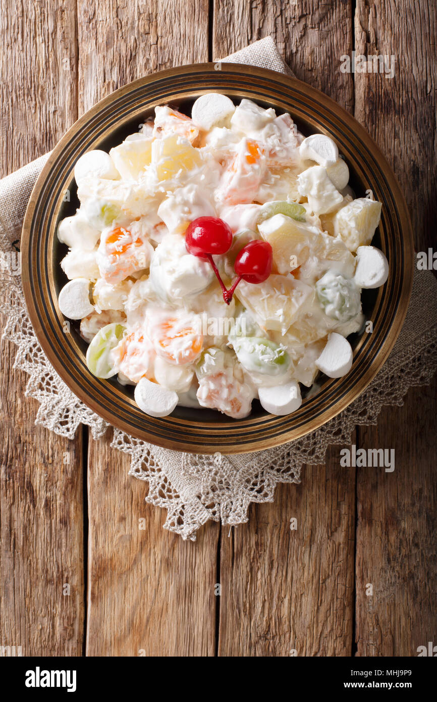 fruit salad Ambrosia from pineapple, tangerine, grapes and marshmelow close-up on a plate. Vertical top view from above Stock Photo