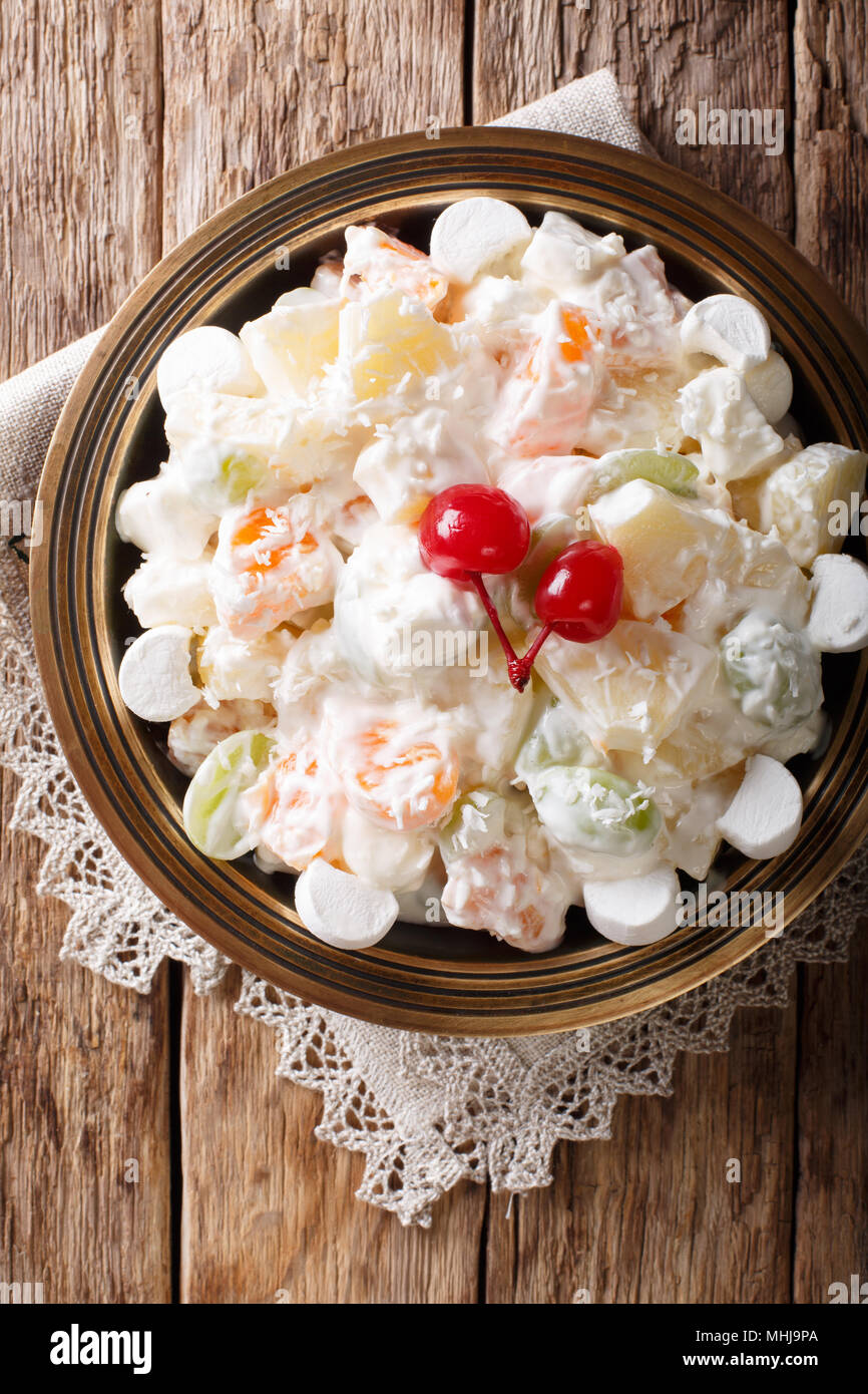 Light fruit salad Ambrosia with marshmallow and vanilla yogurt close-up on a plate. Vertical top view from above Stock Photo