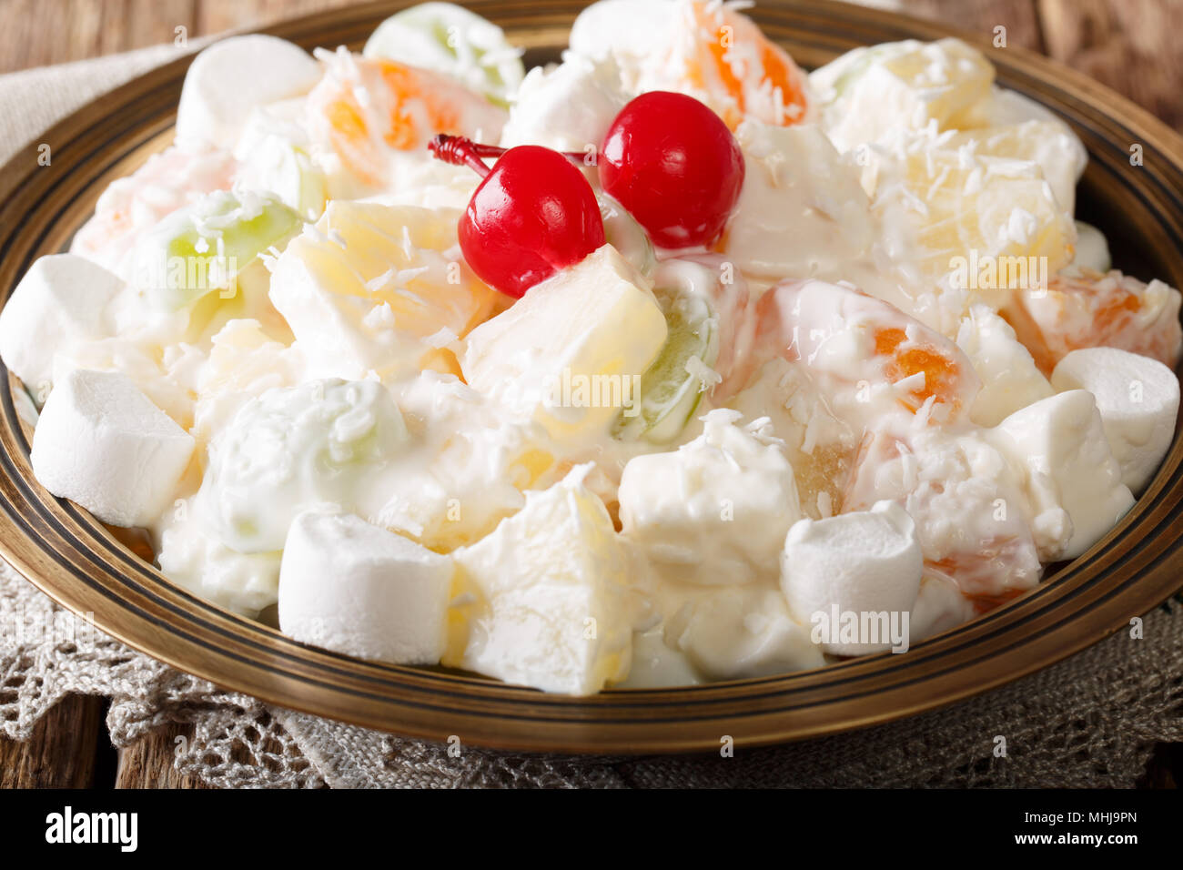 Dessert fruit salad Ambrosia from pineapple, tangerine, grapes and marshmelow with vanilla yogurt close-up on a plate. horizontal Stock Photo