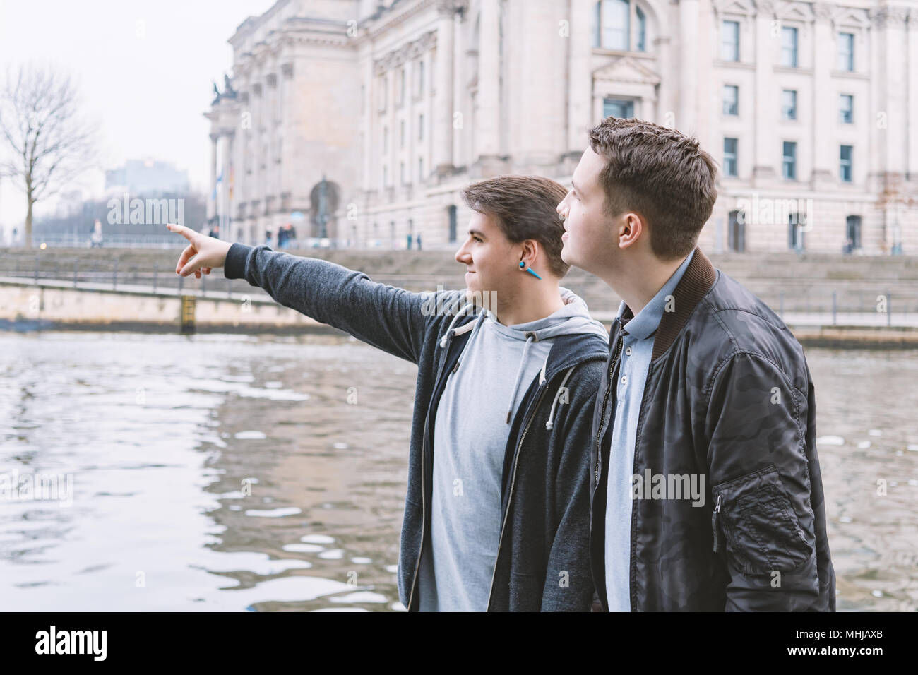 two male tourists exploring government district with Reichstag building and Spree river in Berlin Germany Stock Photo