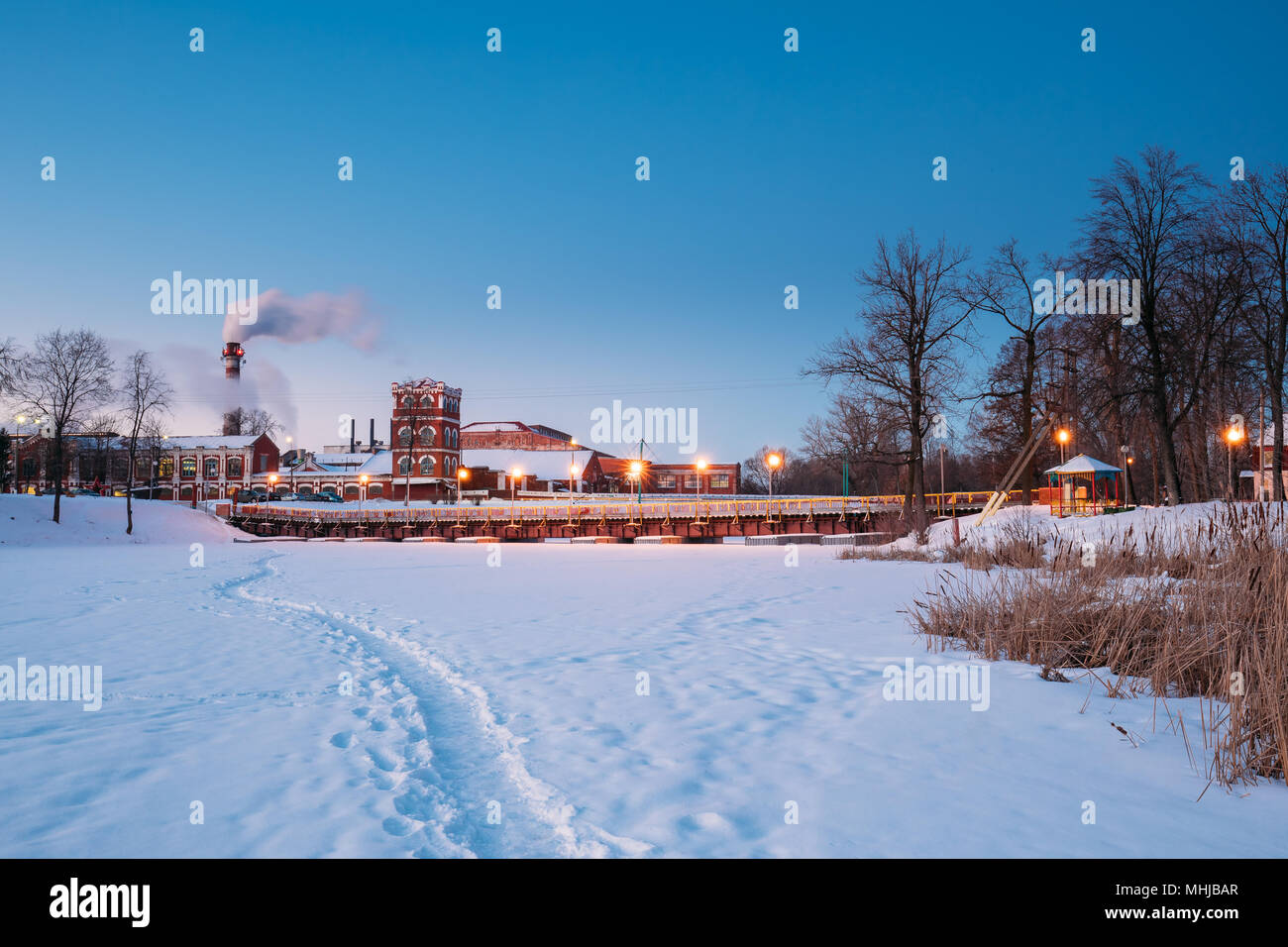 Dobrush, Gomel Region, Belarus. Old Paper Factory At Winter Evening Or Night. Local Landmark In Snowy Winter Landscape. Historical Heritage Stock Photo