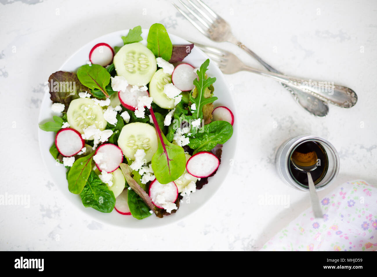 Mixed salad with baby leaves of red lettuce, tatsoi, arugula, red chard, radish, cucumber and feta cheese with olive oil and balsamic vinegar dressing Stock Photo