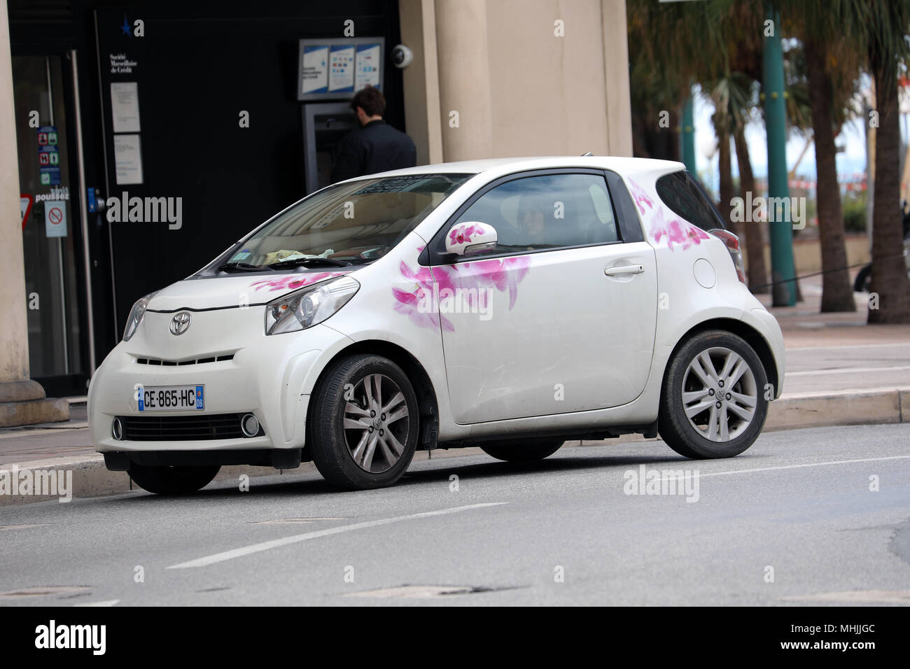 Menton, France - April 5, 2018: Woman Driving a White Toyota iQ With Flowers Stickers in The City Center Of Menton On The French Riviera Stock Photo