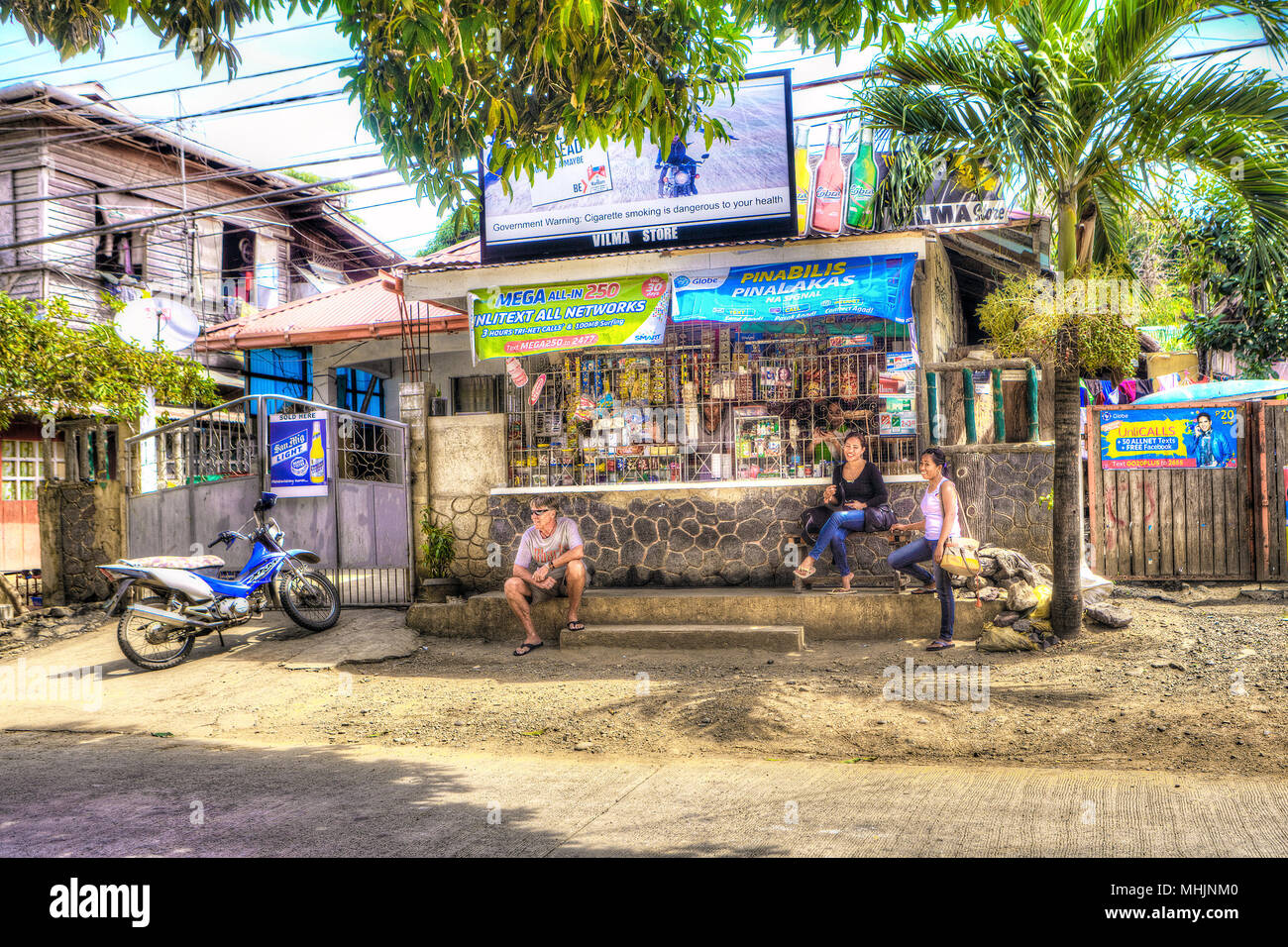 Life in the slow lane for three tourists visiting Puerto Princesa, Palawan, Philippine Islands stopping for a rest at a neighborhood convenience store Stock Photo