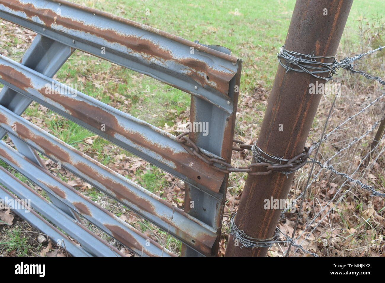 Rusty metal gate preventing access to pasture land on a farm in rural Missouri. Stock Photo