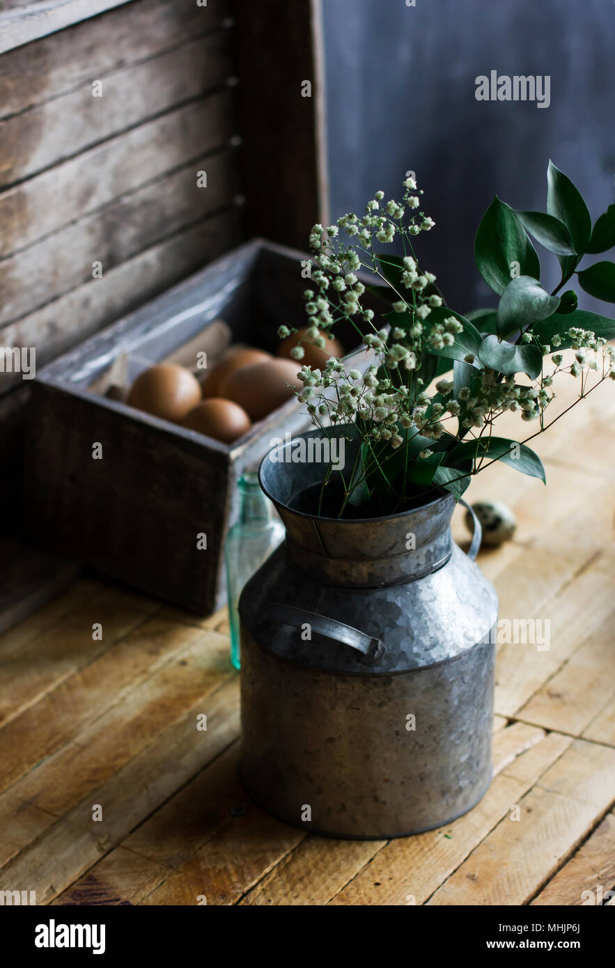 Rustic bouquet of herbs in aluminum cans, chicken eggs in box on the table Stock Photo
