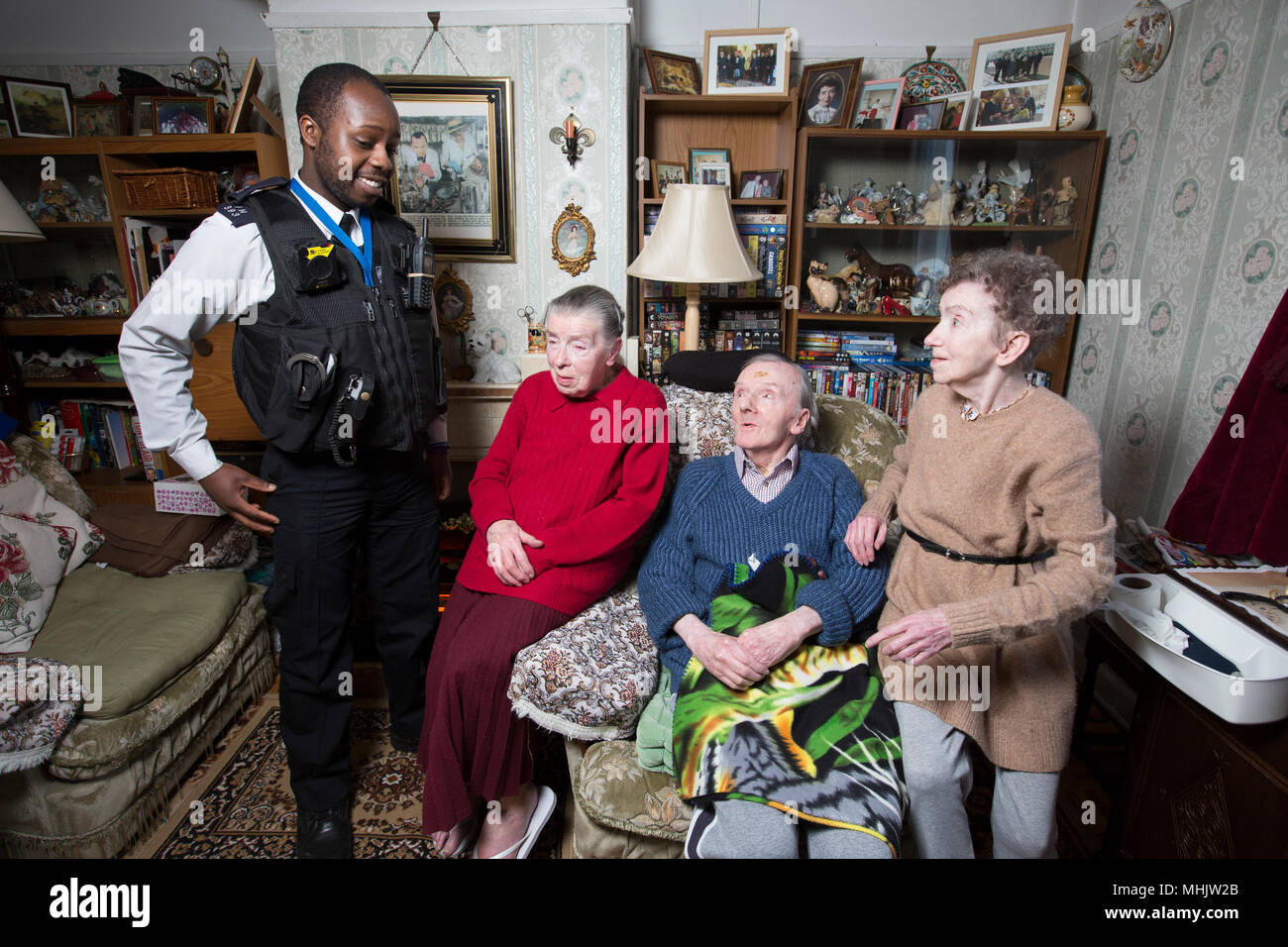 Three elderly siblings being visited by Metropolitan Police officers because they are too scared to leave their house because of burglars, London, UK Stock Photo