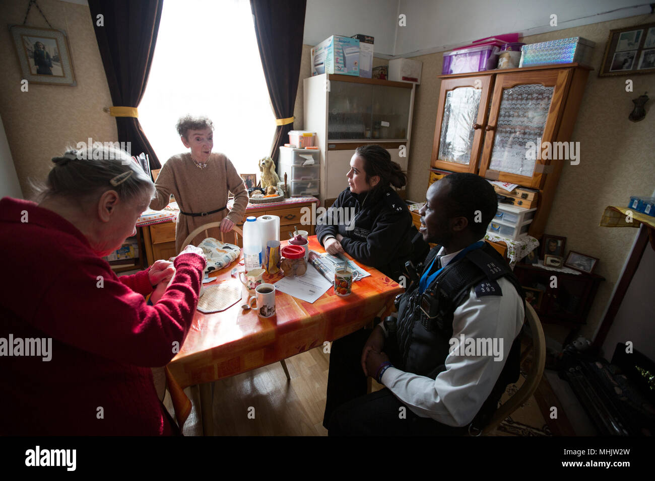 Three elderly siblings being visited by Metropolitan Police officers because they are too scared to leave their house because of burglars, London, UK Stock Photo